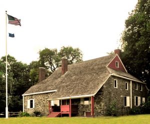 Three story brick farmhouse with white flag pole with USA flag
