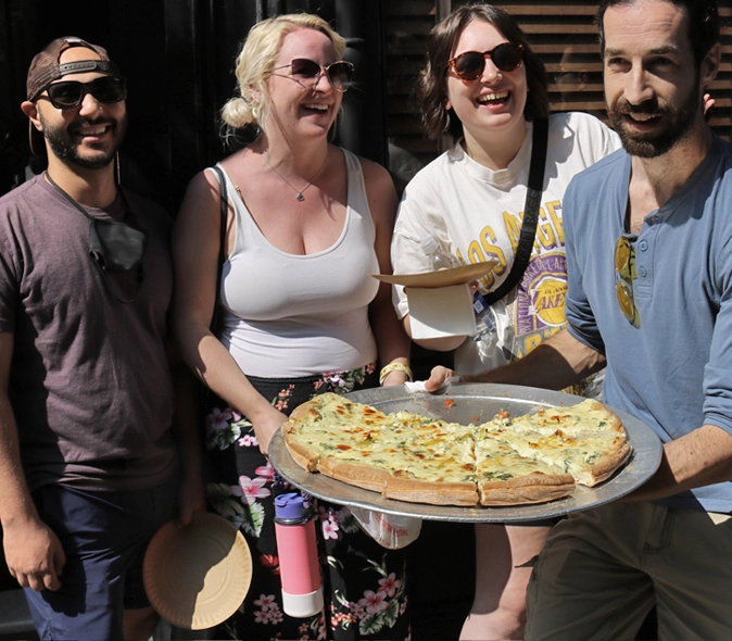 Happy customers with guide holding pizza